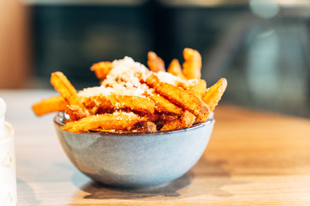 Golden Sweet Potato Fries with Grated Cheese in a Ceramic Bowl in a Restaurant