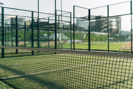 Professional Outdoor Padel Tennis Court with Net and City Buildings Background.