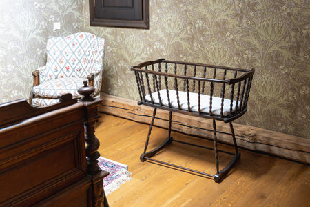 vintage nursery room with wooden cradle armchair and floral wallpaper
