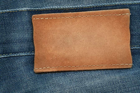 Blank leather jeans label sewed on a blue jeans. Can be used as background for your text.の写真素材