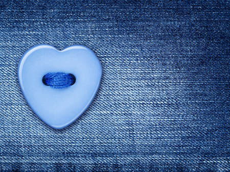 Blue heart shape button, sewed on a denim jeans cloth