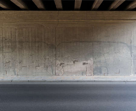 Concrete wall and asphalt road under the bridge.