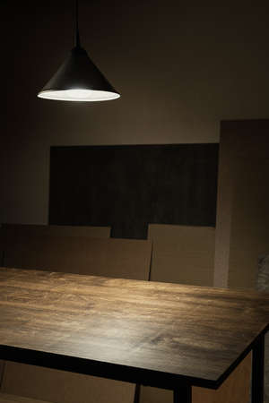 Lamp hanging over empty wooden table in workshop