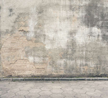 Urban background. Grunge obsolete street wall and pavement.の写真素材