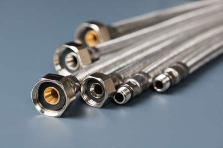 Flexible braided stainless steel water hoses on gray backgroundの写真素材