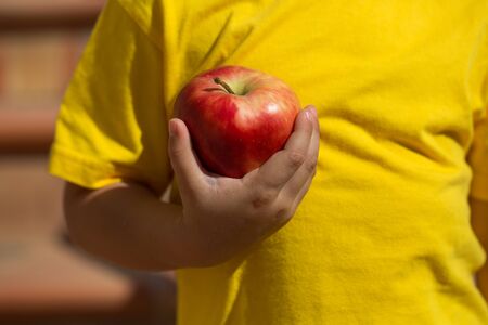 Child with red apple in his hand. Child in yellow dress.