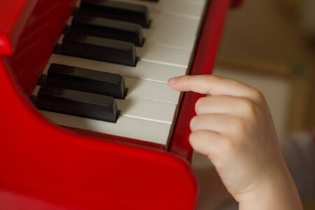 Child hands detail playing red toy pianoの写真素材