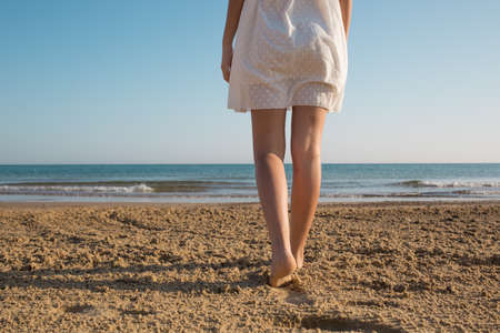 legs of girl in front at the sea, rear viewの写真素材