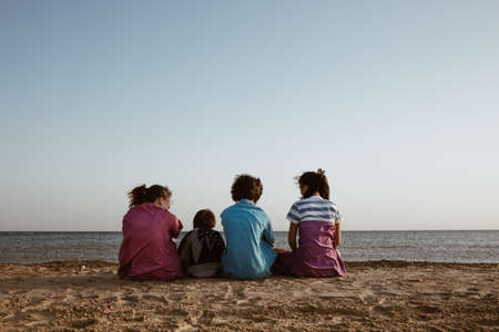 Groups of friends sitting at the beach, rear viewの写真素材