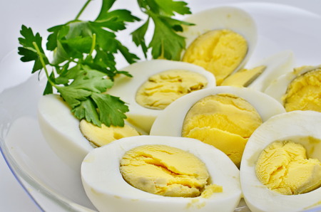 Hard egg halves decorated with parsley - a traditional Passover food normally dipped in salt water and eaten before the mealの写真素材