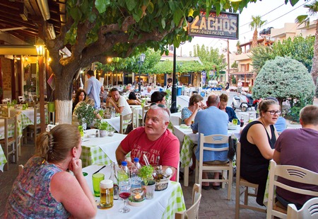 HERSONISSOS, GREECE - JULY 22, 2014: Creten Dinner Time - People eating dinner outdoors in Greek Tavernas at Hersonissos Old City Square in Crete, Greeceのeditorial素材