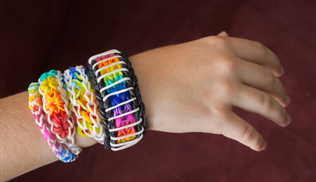 A child's hand decorated with rainbow color loom band rubber braceletsの写真素材