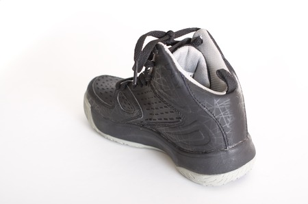 Children's modern high-top black leather and mesh basketball shoes,  sneakers showing the sole, isolated on whiteの写真素材