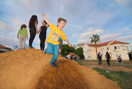 TEL AVIV, ISRAEL - MAY 3, 2015: Elementary school kids playing on a dirt hill near festive Lag Baomer bonfires in a secular suburb of Tel Aviv, Israelのeditorial素材