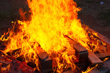 Close up of a bonfire with orange flames and firewood