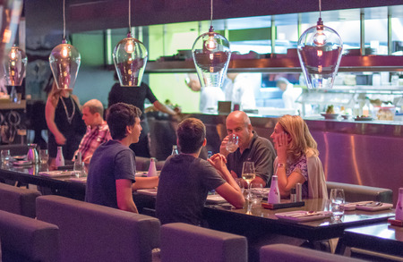 TEL AVIV, SEPT 25, 2015: People having dinner in a modern and chik open kitchen restaurant in...
