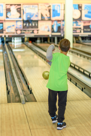 An 8 year old boy enjoying a game of bowling in a retro style bowling alley near Tel Aviv, Israel featuring old-time bowling adds.の写真素材