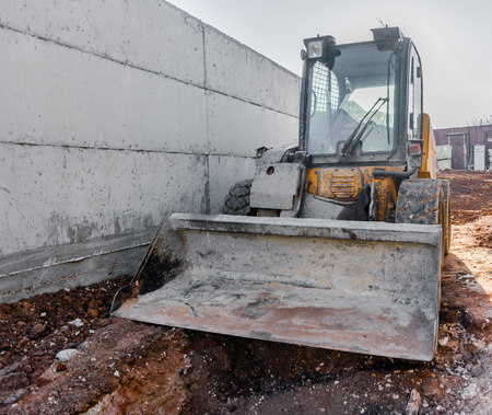 Bulldozer construction machinery in front of a Mediterranean,  brick and concrete house under...