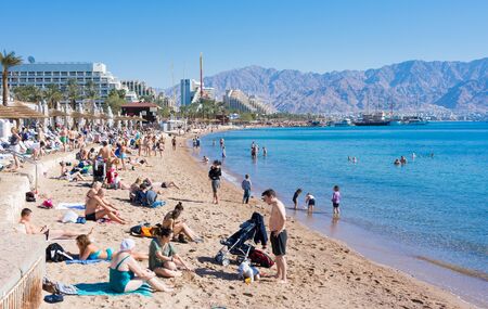 EILAT, ISRAEL - DEC. 29, 2016: People spending their Christmas and New Year vacation bathing and SUP boating in the Red Sea beach of sunny Eilat, Israelのeditorial素材