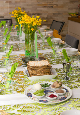 Modern festive Passover Seder table with green  and gold decorations in Tel Aviv, Israel, complete with Matzos and a traditional Seder Plate.の写真素材