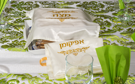 Modern Passover Seder table with green  and gold decorations in Tel Aviv, Israel, complete with Matzos and a traditional Seder Plate.  Matzo covers read "Matzo" and "Afikoman" in Hebrew.の写真素材