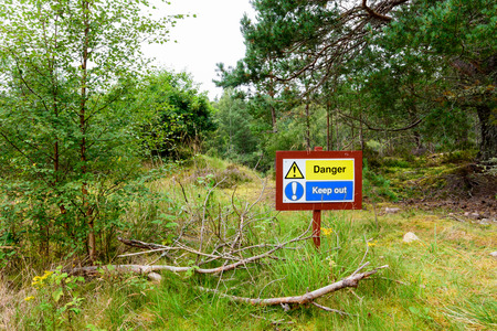 Forest sign reading "Danger! Keep Out!" warning tourist of a river canyon in the Cairngorms National Park, Scotlandの写真素材