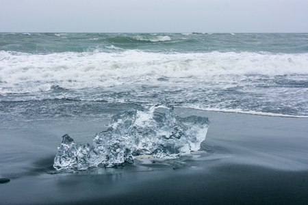 Diamond Beach in South Iceland, where ice that runs to the sea from Jokulsarlon Glaciar Lagoon is washed back to the beach and contrasts beautifully with the black sandの写真素材