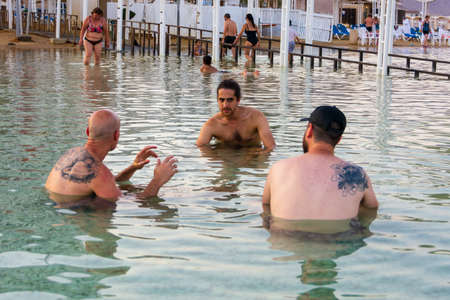 DEAD SEA, ISRAEL - OCT 13, 2019: People swimming, floating, and ejoying the warm waters of the Dead Sea at the evening golden hourのeditorial素材