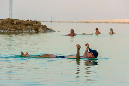 DEAD SEA, ISRAEL - OCT 13, 2019: Elderly people ejoying the warm waters of the Dead Sea at the evening golden hourのeditorial素材