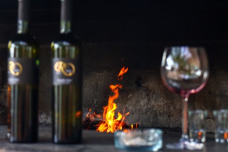Wine bottles and glasses on the background of a burning fire.の写真素材