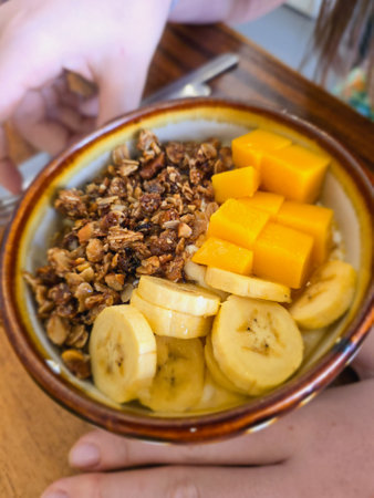 Healthy breakfast with granola, bananas and mango. Selective focus.