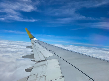 View from the window of an airplane flying above clouds and blue sky