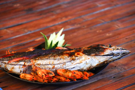 Grilled fish and shrimps on a plate on a wooden table
