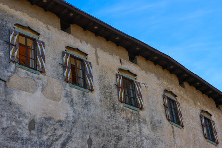Old house with windows and shutters against the blue sky background.の写真素材