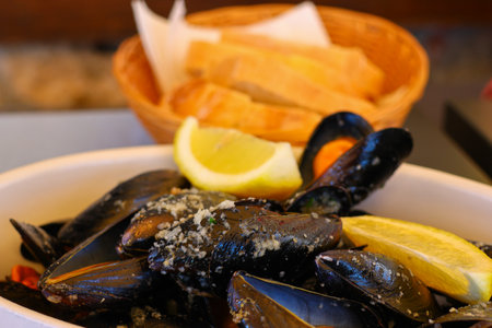 Close up of mussels with lemon and bread in a bowl.の写真素材