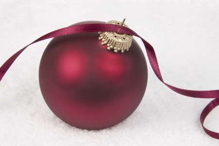 Red Christmas Bauble with Ribbon on snow backgroundの写真素材