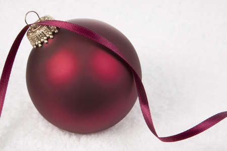 Red Christmas Bauble Ornament on snow backgroundの写真素材