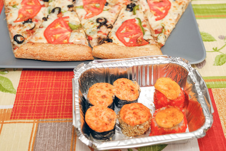 Pizza sushiThe composition on the cutting Board pizza and sushi for fast food. Wooden sticks for sushi. Fresh hot food.の写真素材