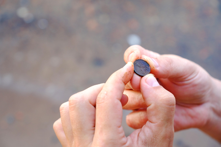 A small coin found in the sand on the shore of the waterの写真素材
