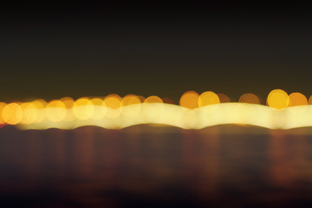 Photography of long-term exposure - night landscape. Night city river. Moon. Is defocused light dots bokeh backgroundの写真素材