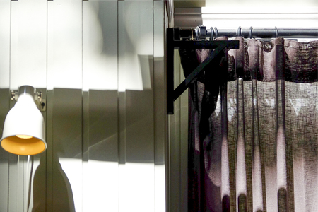 The curtain hangs on a horizontal bar. Against the white wall. Ring mountings.の写真素材