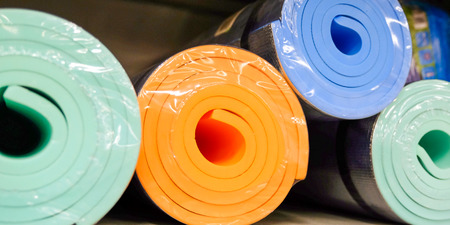 Yoga mats on the wooden table with the sunlight. Packed for saleの写真素材