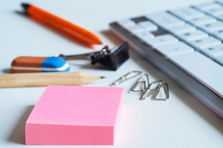 On the table are business items, a calculator, a pen and a pencil with an elastic band. Keyboard for desktop computer. Paper clips buttons and other office, for business.の写真素材
