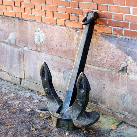 Ancient anchor stands on the ground leaning against the wall.の写真素材