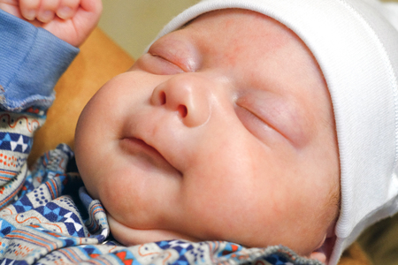 The baby has a Cap on his head, he sleeps peacefullyの写真素材