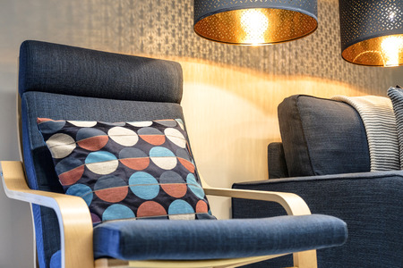 Blue soft chair with pillow, high back reading lamp above the head. Living room interior.