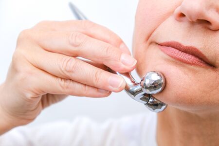 Face massage in spa environment macro. Attractive woman with close eyes taking skin care. Massage...
