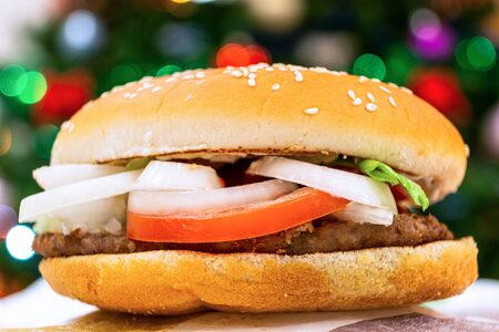Hamburger with a cutlet in a rustic style on the background of a Christmas tree. Healthy organic food. White background. Prepare the soil. Very tasty food. Dietary food. Healthy dinner, lunch. Delicacyの写真素材