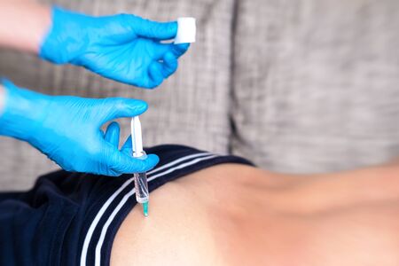 A doctor in medical gloves enters the medicine with a syringe to the patient. Intramuscular...