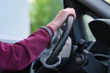 The criminal was caught stealing a car. The hijacker is handcuffed to the steering wheel. The police...